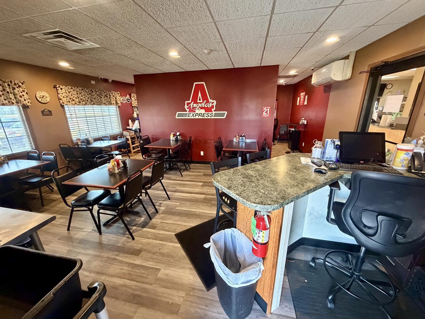 Angelo's Express dining area in Taylorville, Illinois, with tables, chairs and a red Angelo's Express logo wall