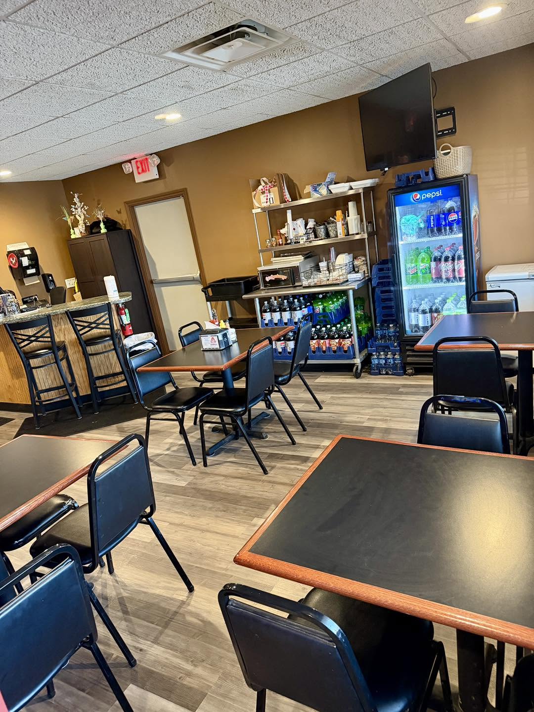 Seating at Angelo's Express with tables, bar stools and a glass-door beverage cooler